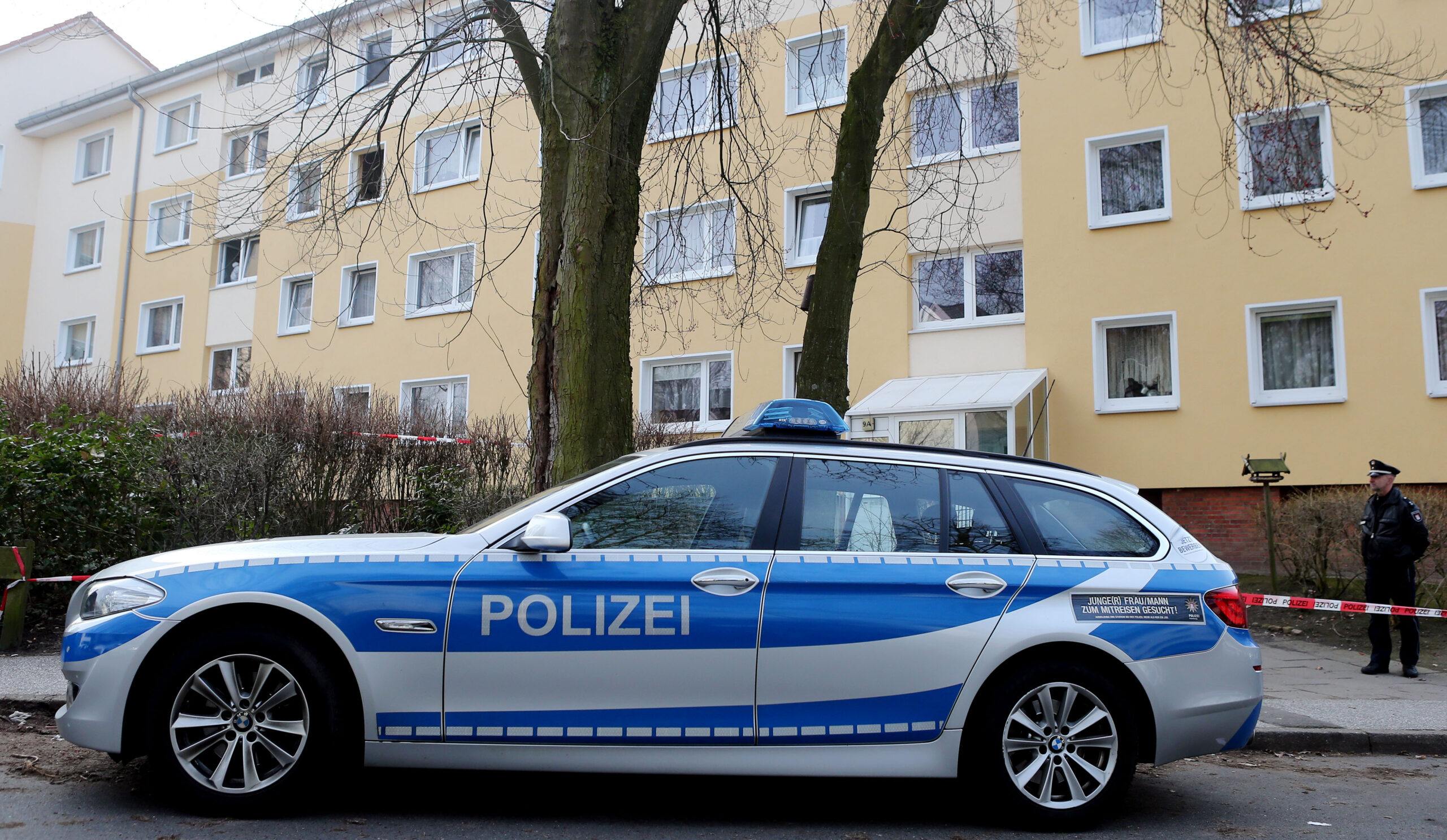 Ein Polizeiwagen steht vor einem Mehrfamilienhaus (Symbolfoto).