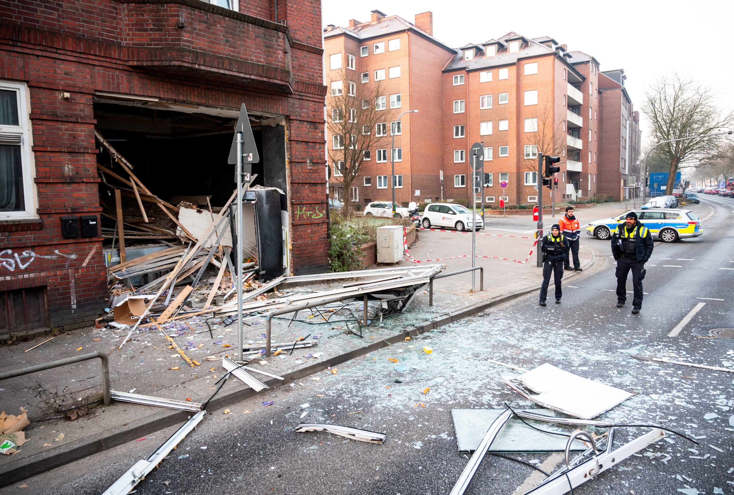 Glasscherben und Trümmerteile liegen nach der Explosion vor dem Mehrfamilienhaus in Wandsbek.