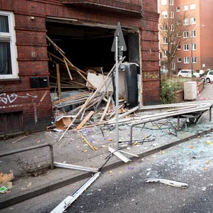 Glasscherben und Trümmerteile liegen nach der Explosion vor dem Mehrfamilienhaus in Wandsbek.