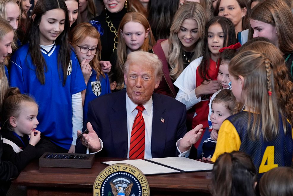 Donald Trump unterzeichnet ein Dekret, umgeben von Mädchen