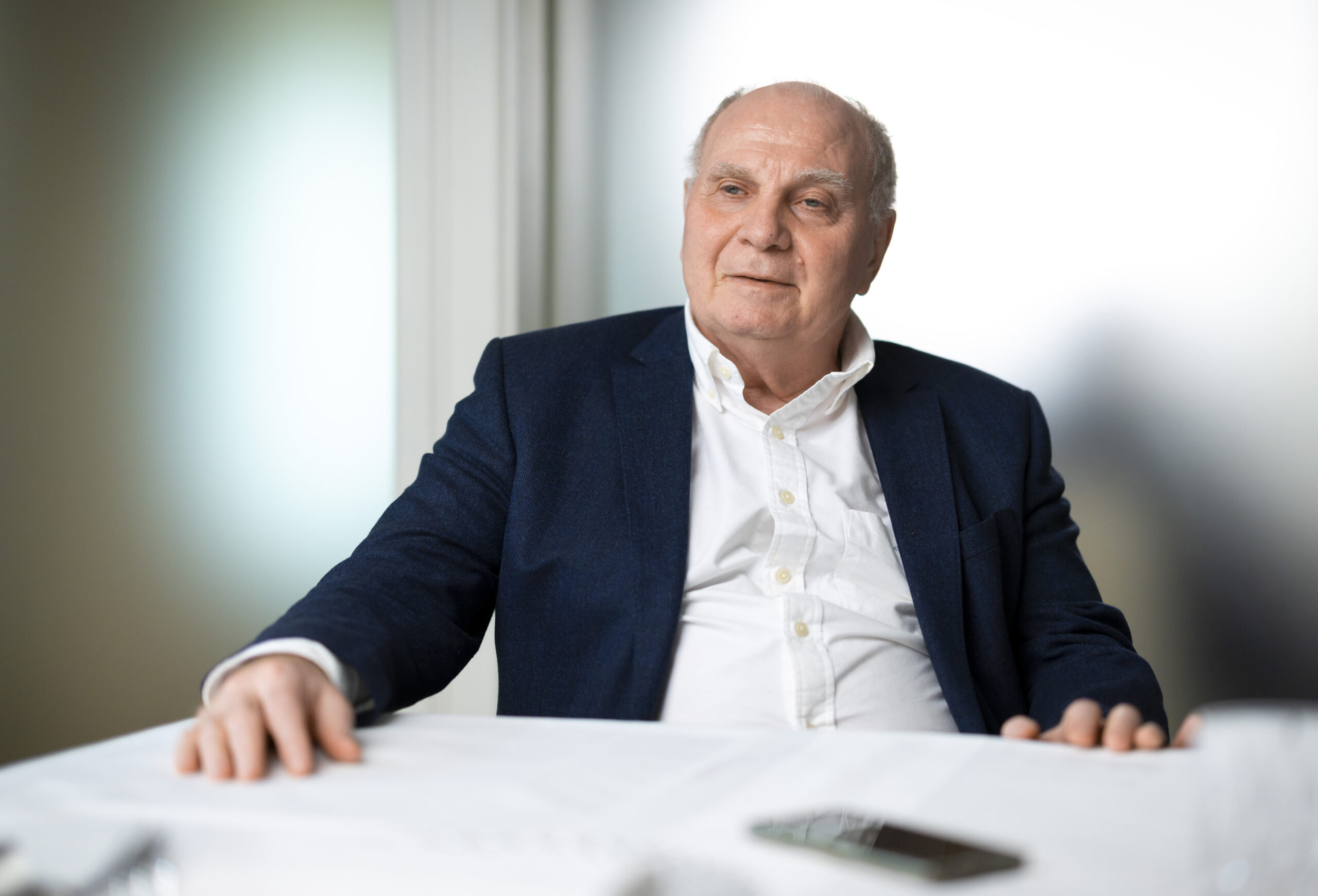 Uli Hoeness sitzt an einem Tisch