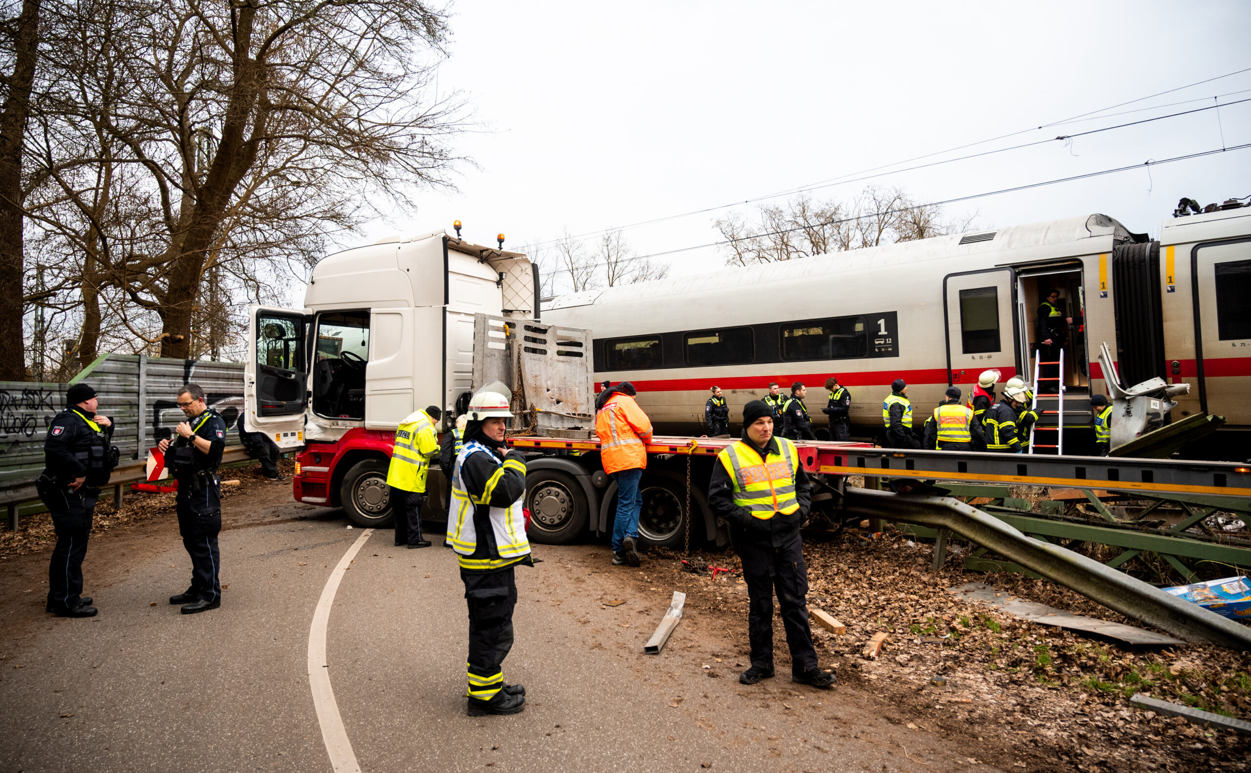 Einsatzkräfte stehen an der Unfallstelle an einem Bahnübergang.