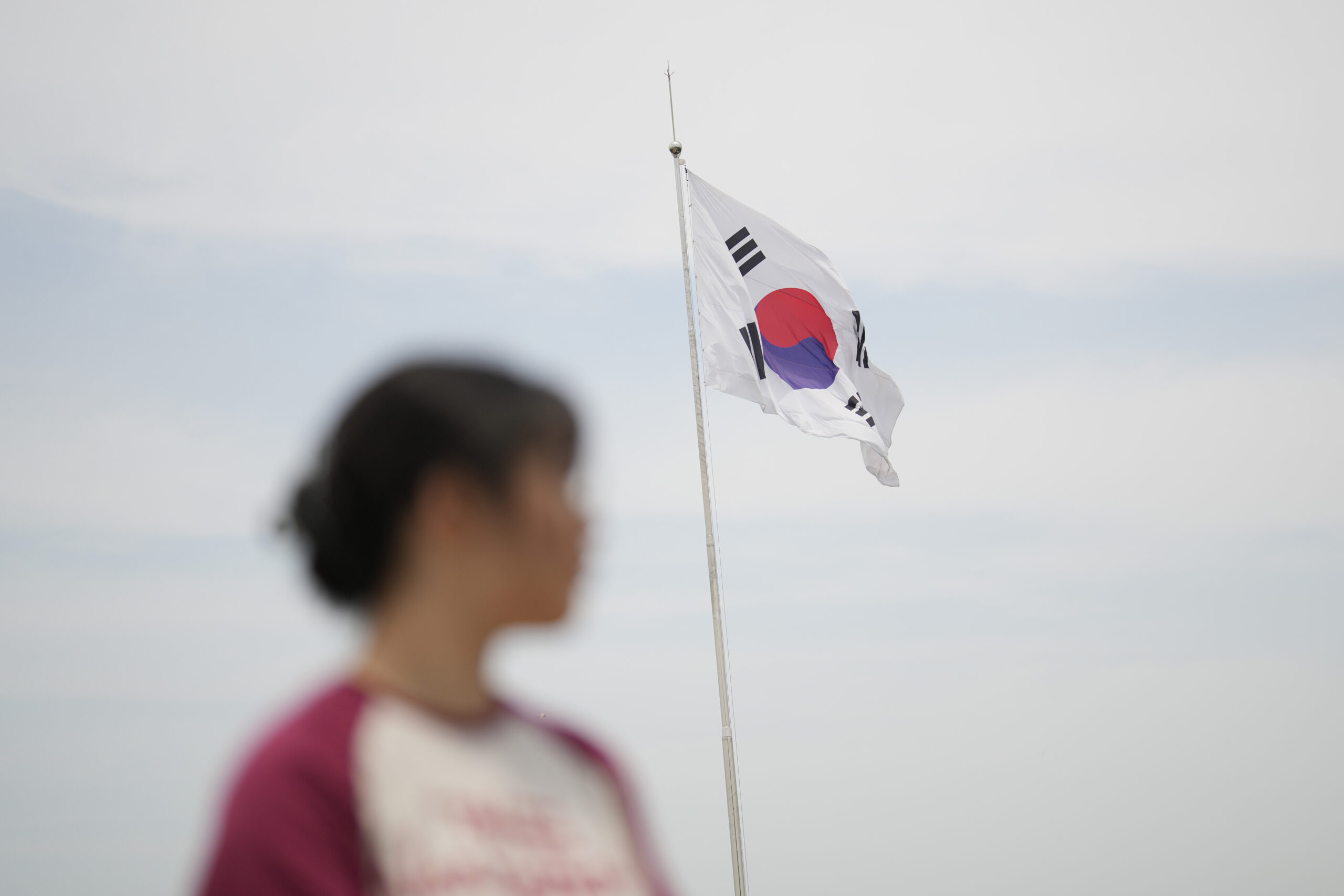 Eine Frau steht vor einer wehenden Flagge Südkoreas.