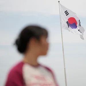 Eine Frau steht vor einer wehenden Flagge Südkoreas.