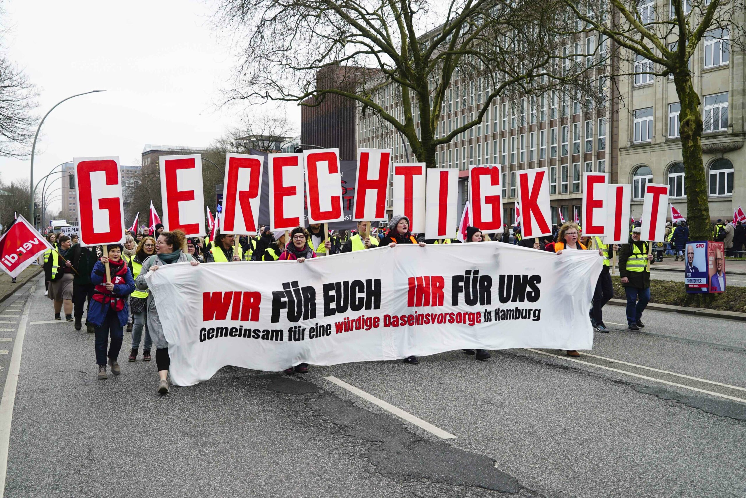 Viele Demonstranten mit Verdi-Flaggen und einem Transparent mit der Aufschrift „Wir für euch, ihr für uns“ stehen am Besenbinderhof.