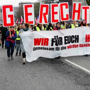 Viele Demonstranten mit Verdi-Flaggen und einem Transparent mit der Aufschrift „Wir für euch, ihr für uns“ stehen am Besenbinderhof.