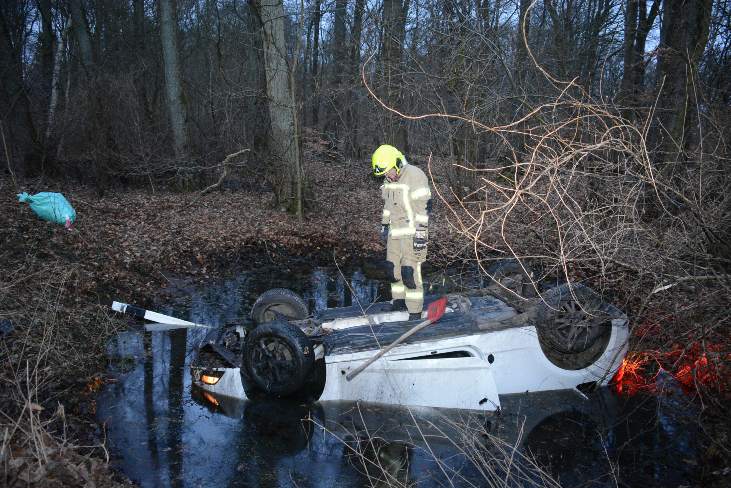 Ein Feuerwehrmann steht auf dem verunfallten Seat.