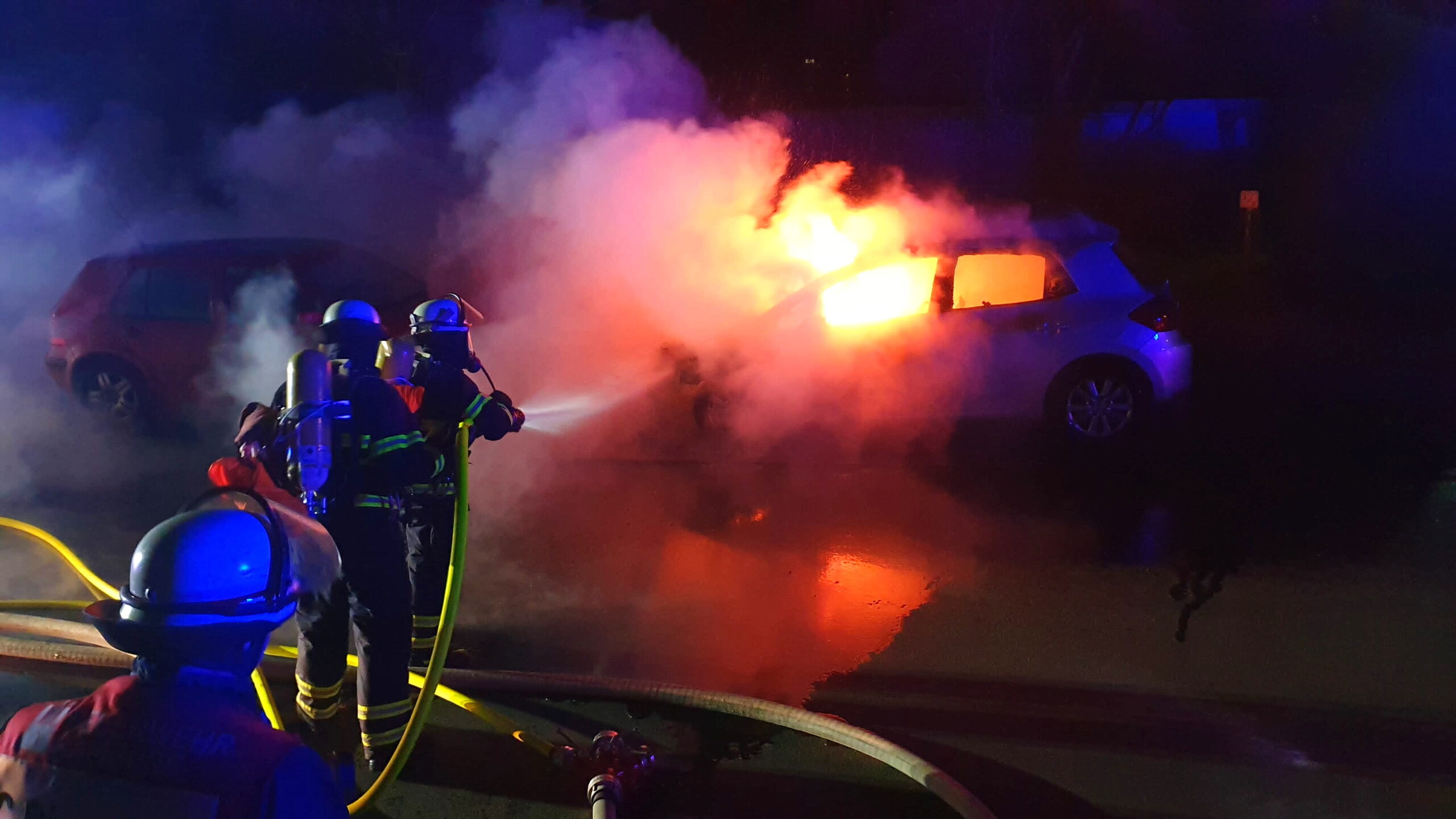 Feuerwehrleute löschen brennendes Auto