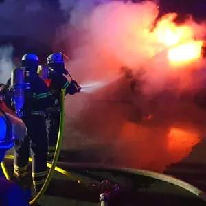 Feuerwehrleute löschen brennendes Auto