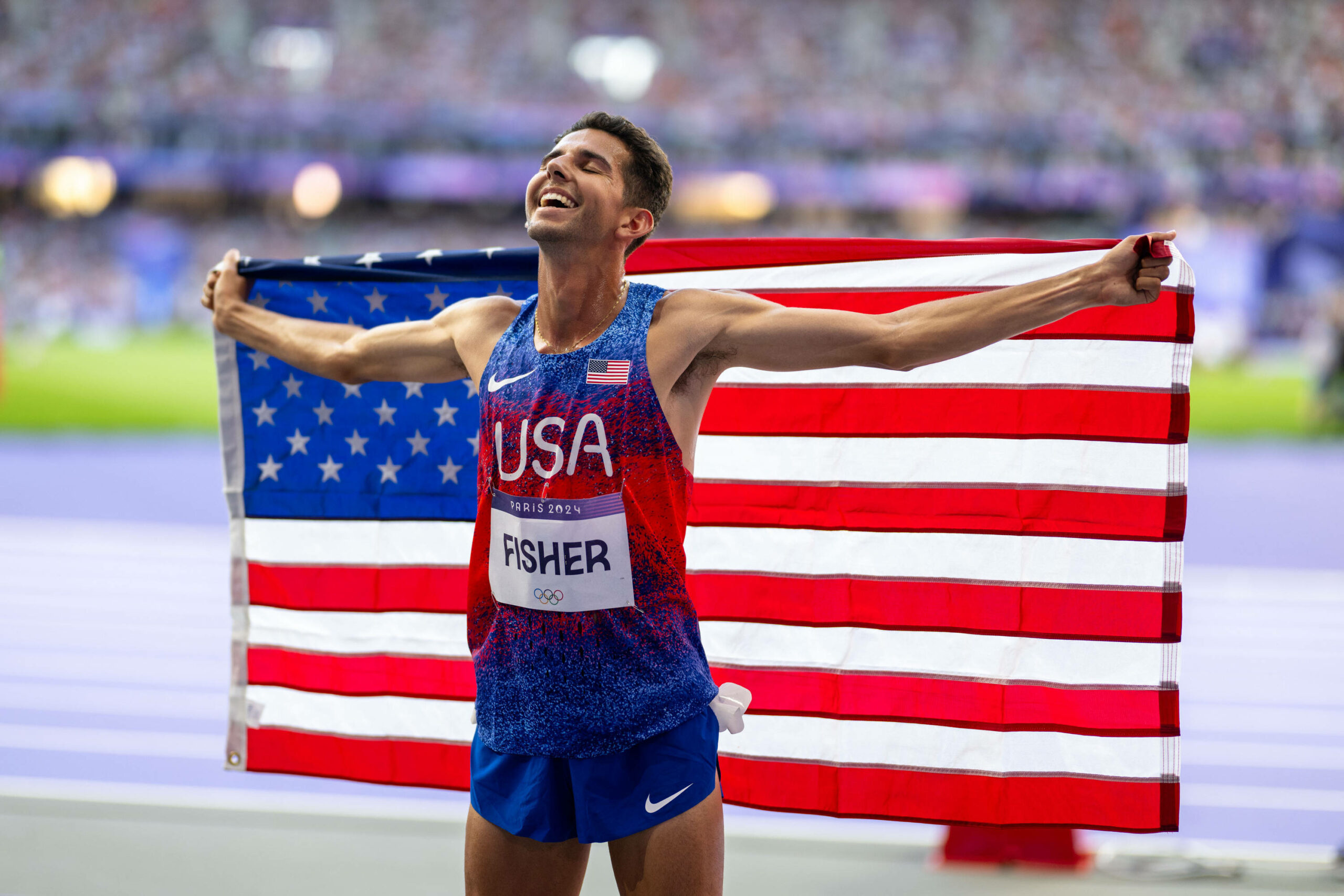 Grant Fisher hält die amerikanische Flagge hinter sich und ist glücklich