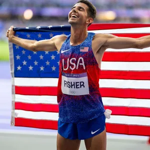 Grant Fisher hält die amerikanische Flagge hinter sich und ist glücklich