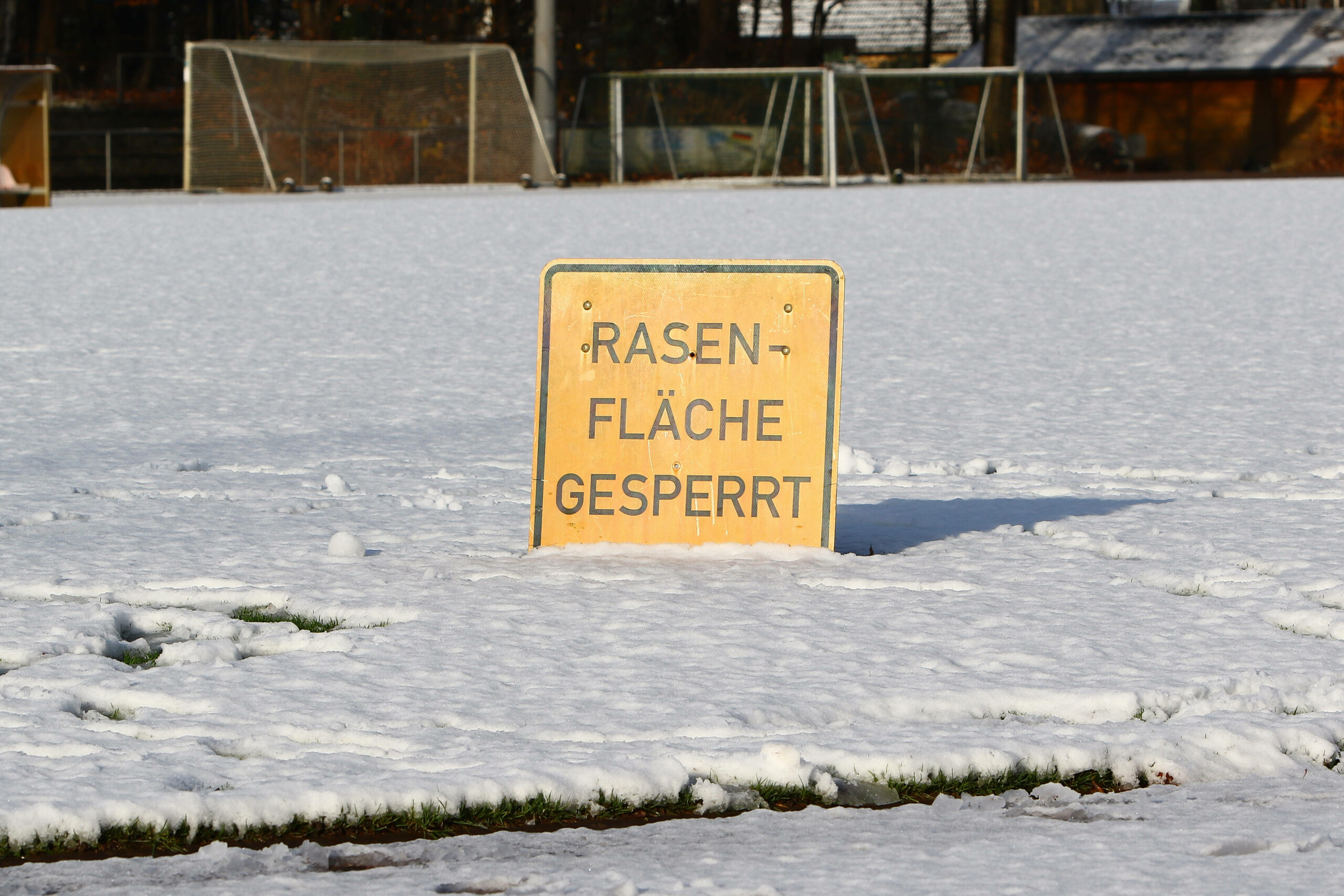 Ein Schild mit der Aufschrift „Rasenfläche gesperrt“ auf einem verschneiten Fußballplatz