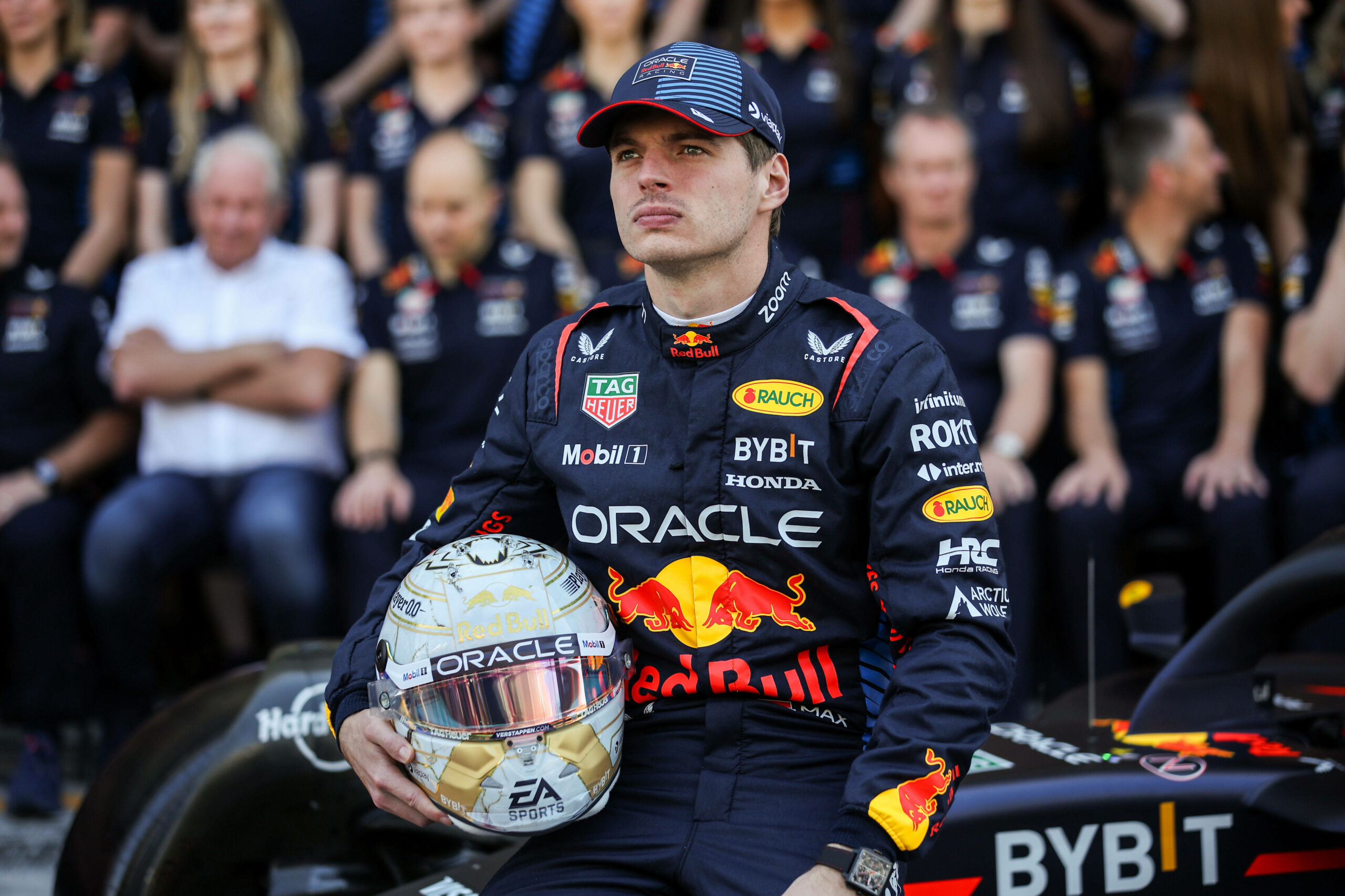 Max Verstappen sitzt mit Helm in der Hand auf seinem Rennauto