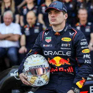 Max Verstappen sitzt mit Helm in der Hand auf seinem Rennauto