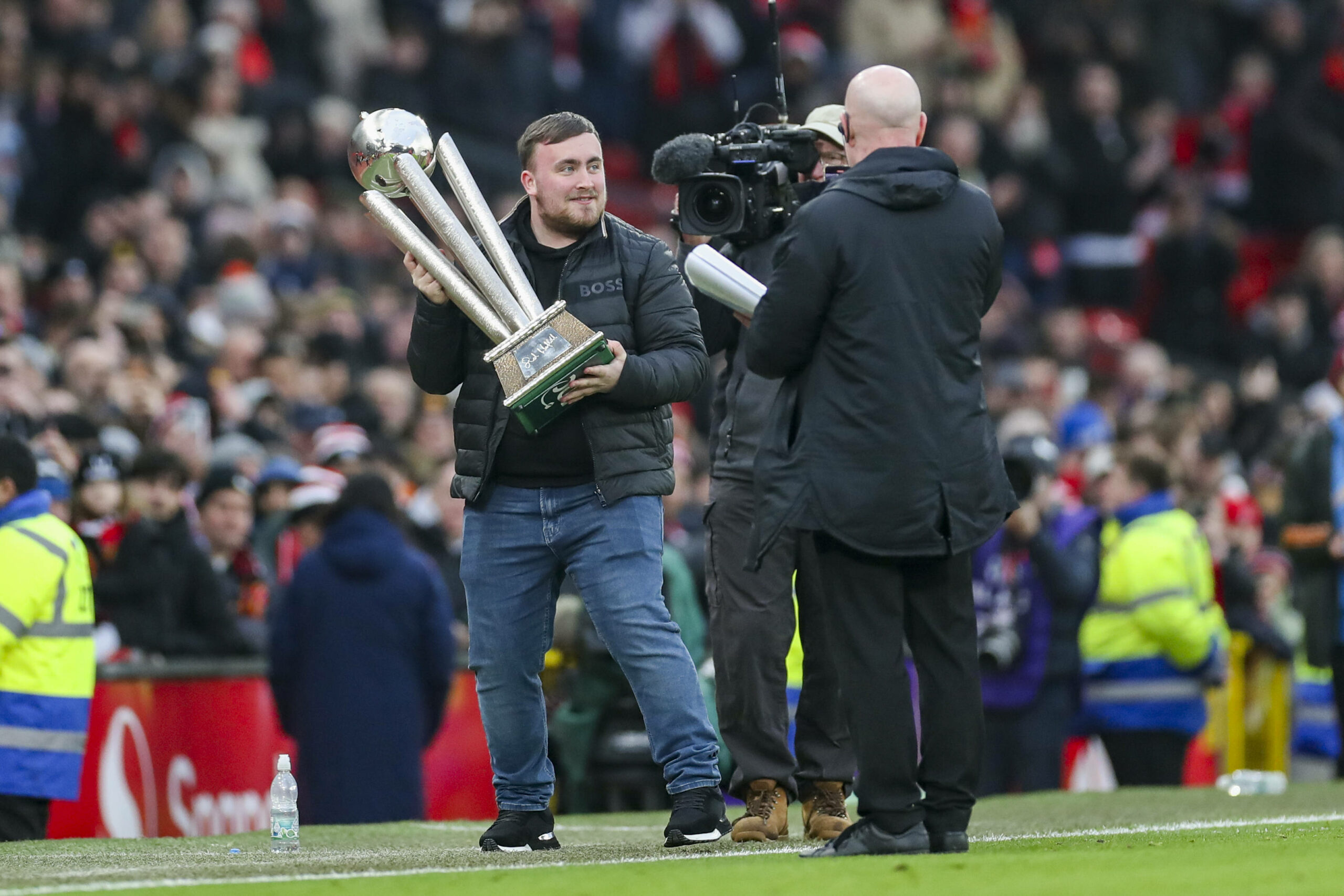 Schon vor einem Premier League-Spiel von Manchester United durfte Luke Littler seinen WM-Pokal präsentieren.