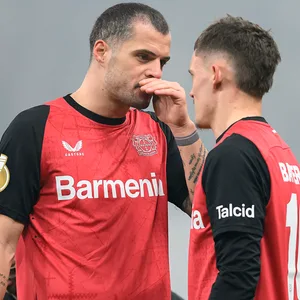 Granit Xhaka tauscht sich mit Florian Wirtz aus, hält sich dabei die Hand vor den Mund.