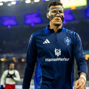 Davie Selke im Aufwärmpullover mit Maske