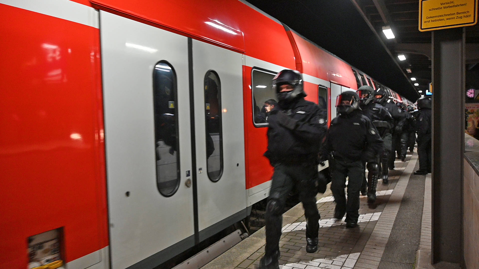 Polizisten laufen am Bahnsteig entlang