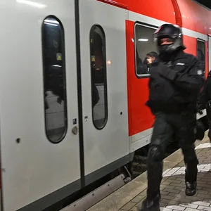 Polizisten laufen am Bahnsteig entlang