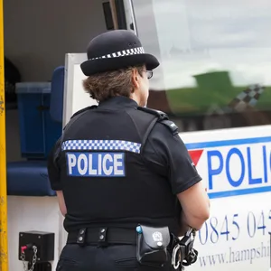 Eine Beamtin der britischen Polizei steht an einem Einsatzfahrzeug.