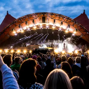 Besucher des „Roskilde“-Festivals feiern vor einer Bühne.
