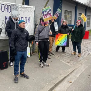 Ein Gruppe Demonstranten hat sich gegenüber des Eingangs aufgestellt.