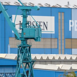 Wolgast: Das Logo der Lürssen-Werft hängt an einer Schiffbauhalle der Peene-Werft.