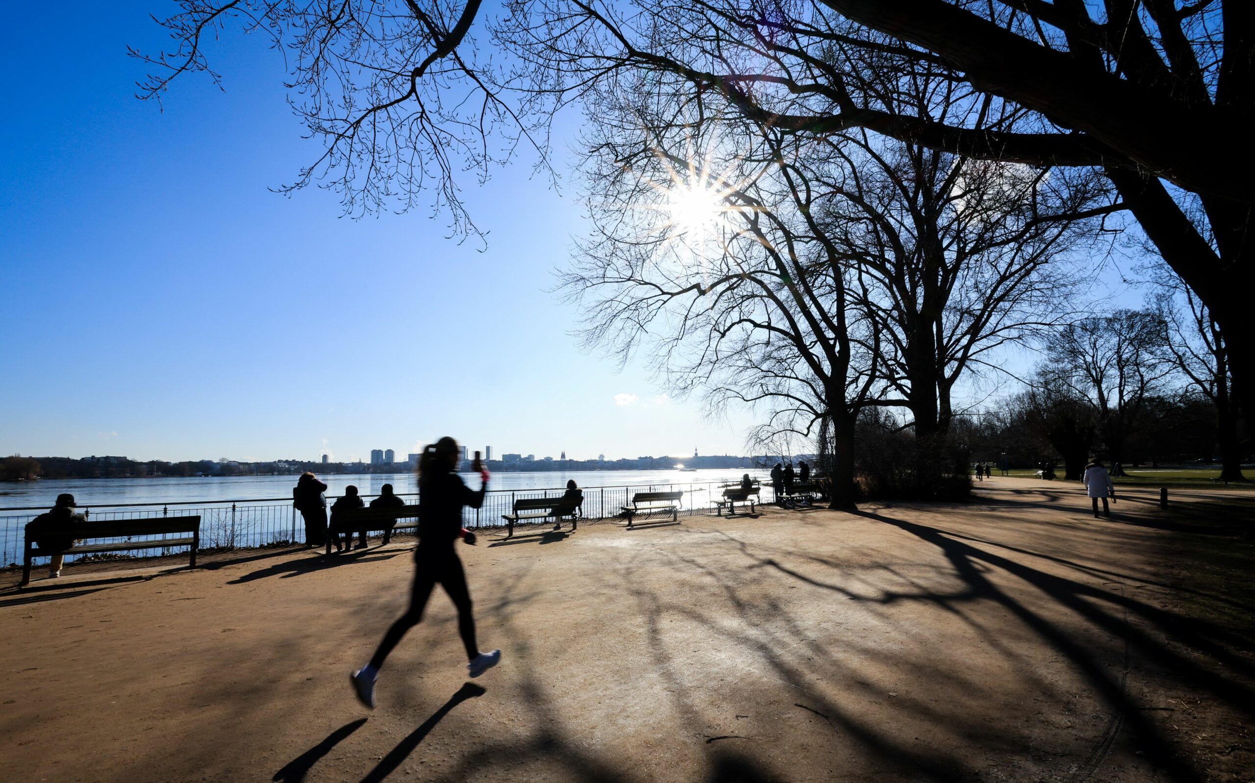 Jogger und Spaziergänger genießen an der Alster in Hamburg die Sonne – trotz Bibber-Kälte.