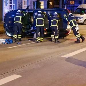 Einsatzkräfte der Feuerwehr richten das umgekippte Unfall-Fahrzeug wieder auf.