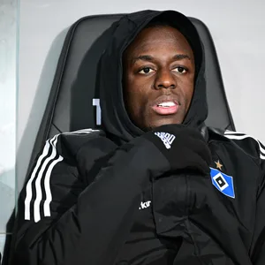 Jean-Luc Dompé sitzt mit Kapuze auf dem Kopf auf der HSV-Bank