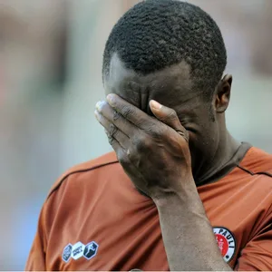 Gerald Asamoah vergräbt sein Gesicht in seiner linken Hand das St. Pauli-Trikot tragend.