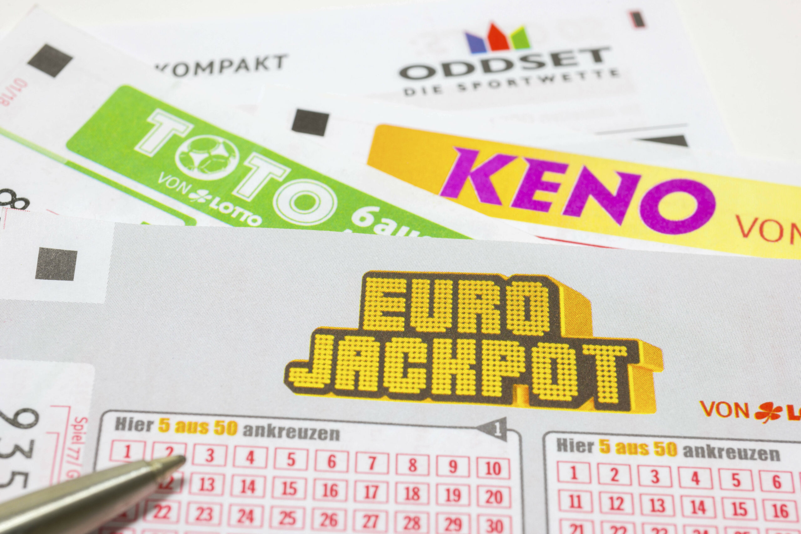 Mehrere Lotto-Spielscheine mit einem Kugelschreiber