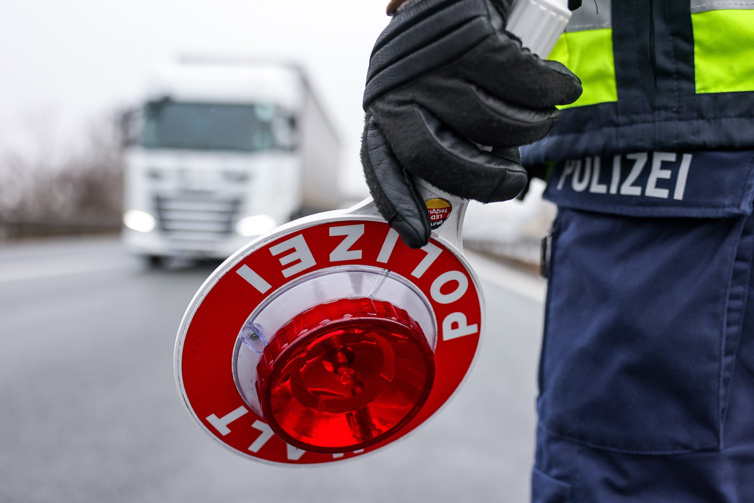 Ein Polizist hält eine Polizeikelle für eine Kontrolle an der Autobahn.