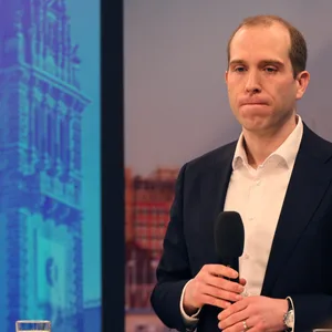 Mann mit Mikro in einem TV-Studio, ernstes Gesicht