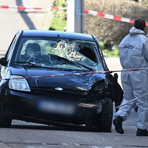 Beamte der Spurensicherung untersuchen ein beschädigtes Fahrzeug an einer Zufahrt zur Mannheimer Rheinbrücke.