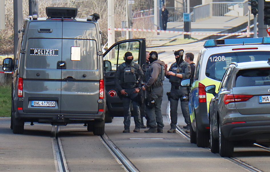 Beamte des Entschärfungsdienstes der Polizei stehen in der Nähe eines beschädigten Fahrzeugs vor einer Zufahrt zur Mannheimer Rheinbrücke.