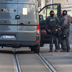 Beamte des Entschärfungsdienstes der Polizei stehen in der Nähe eines beschädigten Fahrzeugs vor einer Zufahrt zur Mannheimer Rheinbrücke.