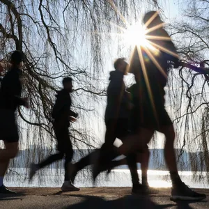 Ein Laufgruppe joggt bei strahlendem Sonnenschein an der Außenalster.