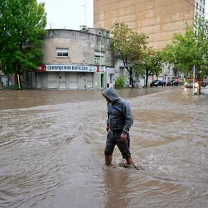 Ein Mann watet durch das Knie-hohe Wasser. Die komplette Straße ist überschwemmt.