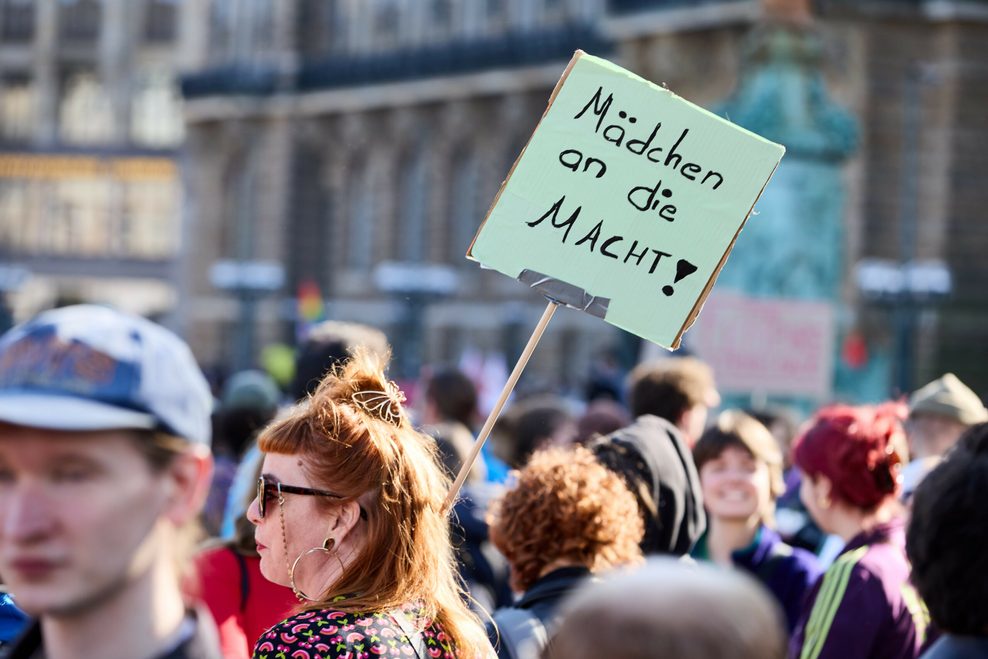 Eine Teilnehmerin hält auf dem Rathausmarkt ein Tranaparent mit der Aufschrift „Mädchen an die Macht!“.