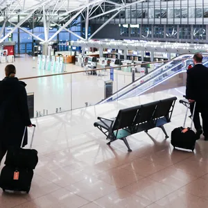 Crewmitglieder einer Fluglinie gehen durch den nahezu menschenleeren Terminal 1 am Flughafen Hamburg.
