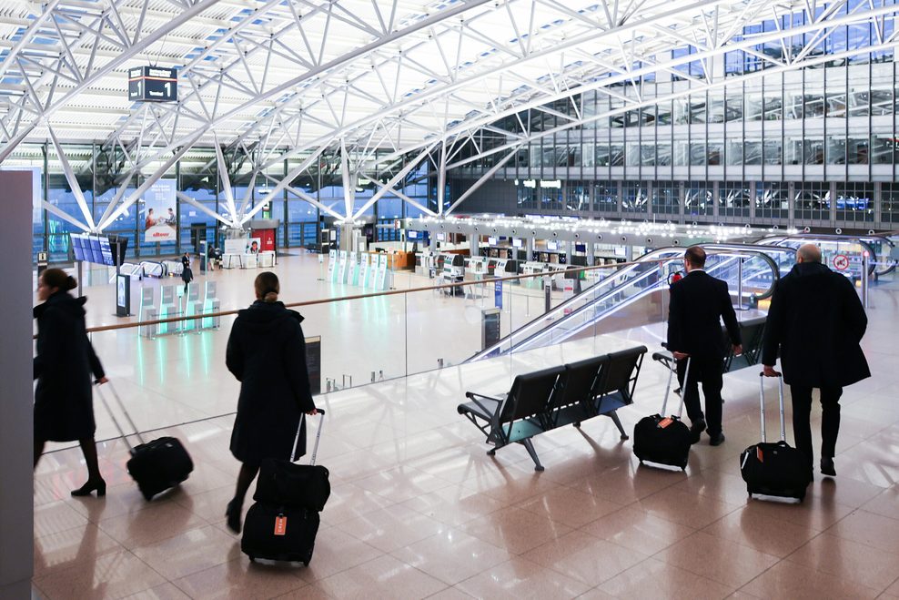 Crewmitglieder einer Fluglinie gehen durch den nahezu menschenleeren Terminal 1 am Flughafen Hamburg.