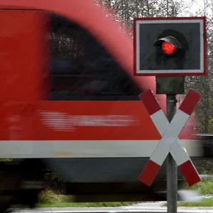 Ein Zug fährt über einen unbeschrankten Bahnübergang.