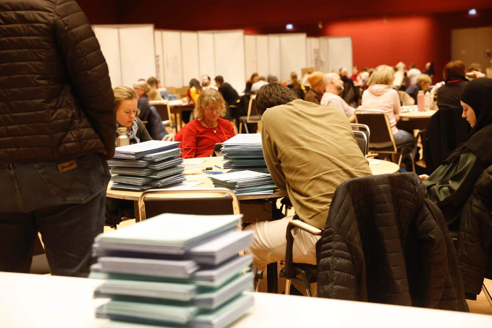 Wahlhelfer sitzen an Tischen mit Briefwahl-Unterlagen