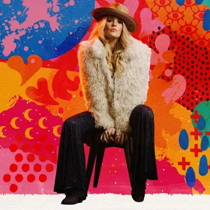 Elles Bailey sitzt auf einem Hocker vor einem bunten Hintergrund.