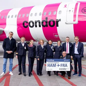 Mitarbeiter des Hamburger Flughafens und der Fluggesellschaft Condor stehen vor einem Condor-Flugzeug.