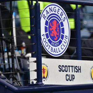 Das Logo der Glasgow Rangers vor einem Tribünen-Zaun