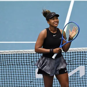 Naomi Osaka klatscht auf ihren Tennisschläger und lacht