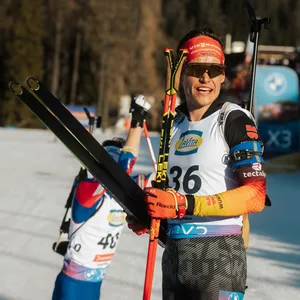 Philipp Horn schaut mit Skiern in der Hand Richtung Sonne