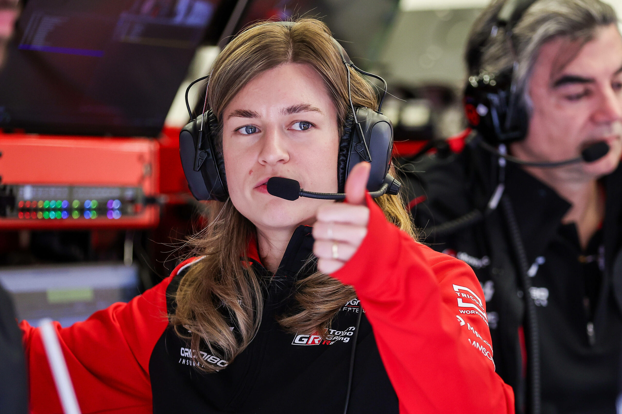 Haas-Renningenieurin Laura Müller macht den Daumen hoch mit Headset auf dem Kopf